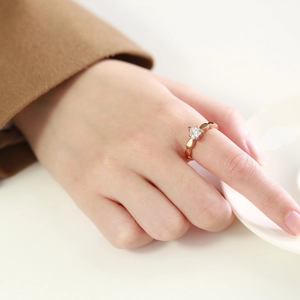 Detail shot of heart-shaped rose gold ring with zircon stone worn on a finger