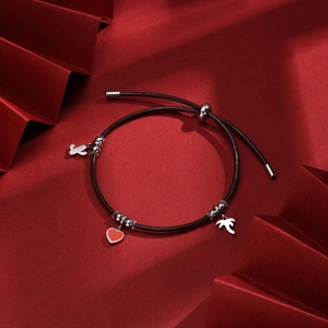 Detailed view of black leather bracelet with heart, cactus and palm tree charms