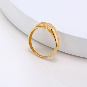Gros plan d'une chevalière en forme de cœur finition or 18 carats avec texture brossée