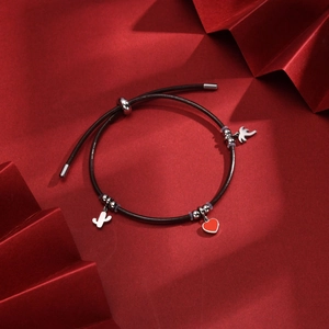 Detail of adjustable black cord bracelet with heart, cactus and bird charms