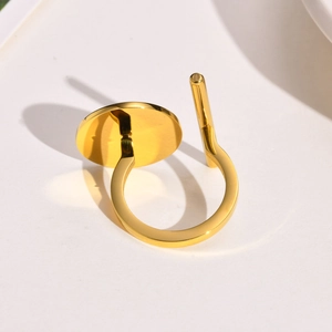 Close-up of golden geometric ring with polished disc and vertical bar on beige background