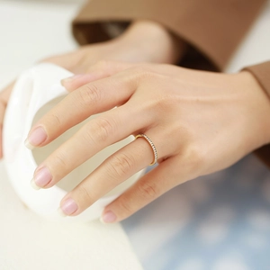 Close-up of minimalist gold stainless steel ring with half-circle zircon pavé on model