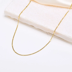 Detail of double-layer gold stainless steel necklace with flat rectangular accents