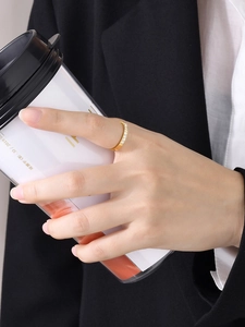 Bague fine dorée avec zircons blancs portée à la main tenant une tasse de café chic