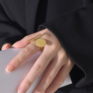 Detail of a minimalist gold geometric ring featuring a polished round surface and bar design