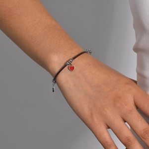Close-up of adjustable cord bracelet with silver beads and a red heart charm on wrist