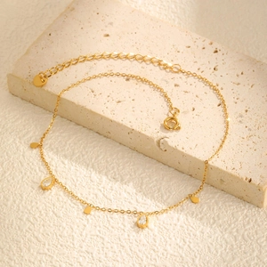 Gold stainless steel anklet with teardrop zircon and leaf pendants on beige stone