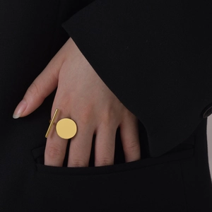 Minimalist gold geometric ring featuring a circular disc and parallel bar on a hand