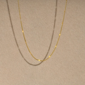 Close-up of golden stainless steel flat curb chain texture on velvet background
