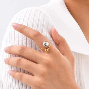 Dettaglio dell'anello dorato regolabile con sfere metalliche a contrasto oro e argento
