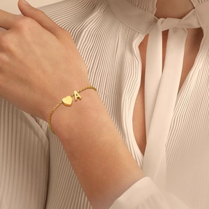 Gros plan détaillé du bracelet en or 18 carats avec pendentifs cœur et lettre A
