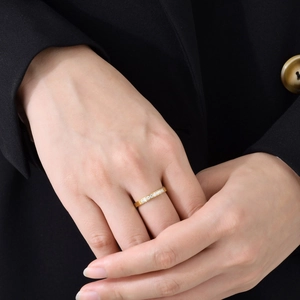 Gros plan d'une bague dorée minimaliste sertie de zircons blancs sur la main