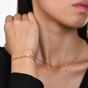 Close-up of a layered gold chain necklace and bracelet set with fine metal beads