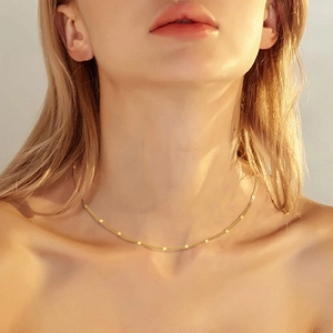 Close-up of gold double-layer chain necklace with flat round discs on a female model