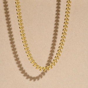Detailed view of golden wheat link chain necklace with elegant heart-shaped metal pieces