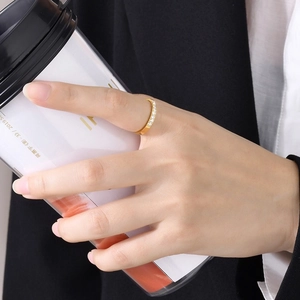 Bague minimaliste en acier doré avec zircons portée à la main tenant un café