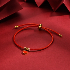 Detail of red cord bracelet with gold heart pendant and adjustable metal slider