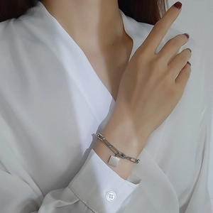 Gros plan d'un bracelet à maillons trombone avec un pendentif carré poli