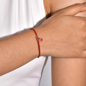 Close-up of red adjustable leather bracelet with gold beads and heart pendant on wrist