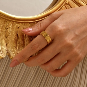 Nahaufnahme eines 18K vergoldeten breiten strukturierten Kettengliedrings am Finger