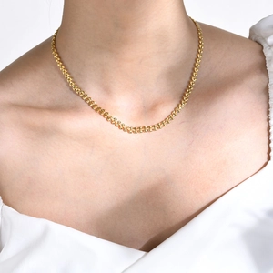 Detailed view of a gold wheat chain necklace worn as a collar necklace on a model