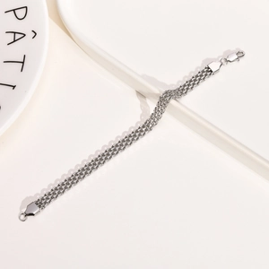 Detail of silver triple-strand stainless steel mesh bracelet with lobster clasp on ceramic