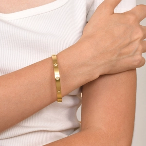 Bracciale rigido in acciaio dorato lucido con zirconi quadrati indossato da modella