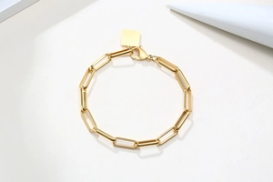 Gros plan d'un bracelet trombone en or 18 carats avec un pendentif carré poli