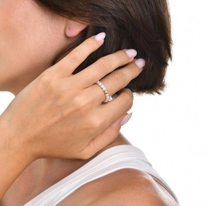 Détail d'une bague en perles avec bille dorée portée par un mannequin sur fond blanc