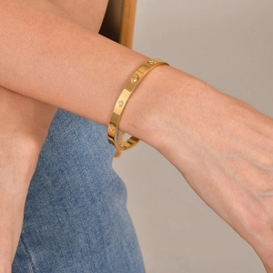 Dettaglio di un bracciale in acciaio inossidabile dorato con zirconi quadrati sul polso