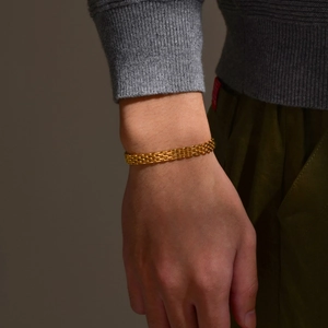 Close-up of golden stainless steel mesh strap bracelet worn on wrist with luxury texture
