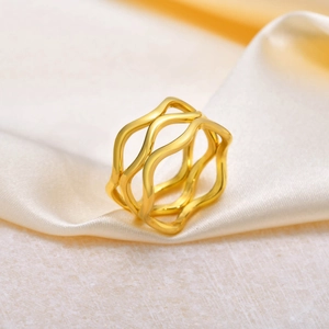 Macro detail of multi-layered wavy gold ring on elegant silk and stone textures
