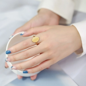 Close-up of a minimalist gold oval ring on a hand with floral nail art for a refined look