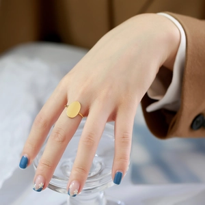 Detail of a gold-plated oval ring on woman's hand, minimalist aesthetic with smooth finish