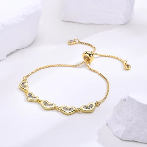 Detail of adjustable gold heart bracelet with sparkling zircon stones on stone background