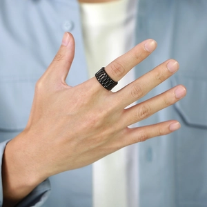 Gros plan d'une bague noire style bracelet de montre avec texture de maillons au doigt