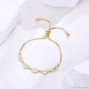 Detail of adjustable gold-plated bolo bracelet with heart-shaped cubic zirconia charms
