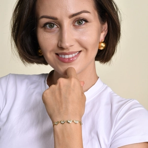 Detail of gold heart link bracelet with zircons and ball studs on a model