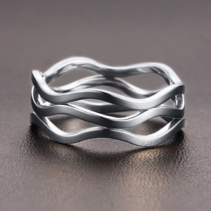Close-up of a silver multi-layer wavy stainless steel ring on a textured leather surface
