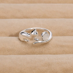 Adjustable silver cat ring with moonstone detail on beige velvet display stand