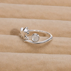 Macro shot of silver cat ring with moonstone on a beige velvet jewelry display