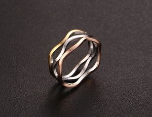 Macro shot of a tricolor stainless steel ring featuring wavy gold, silver, and rose gold bands