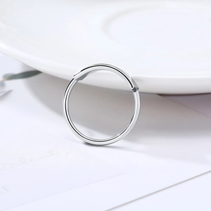 Close-up of polished silver minimalist hinged ring on a white minimalist background