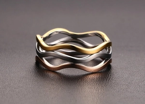 Macro detail of three-layer wavy rings in gold, silver, and rose gold stainless steel