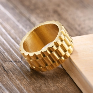 Détail d'une bague large en acier inoxydable doré avec texture de bracelet montre