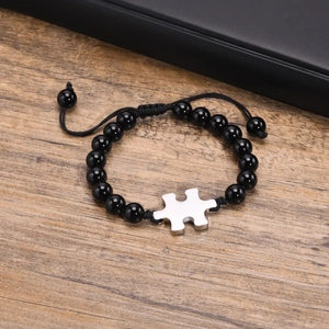 Macro detail of black beaded bracelet with silver puzzle charm and adjustable cord