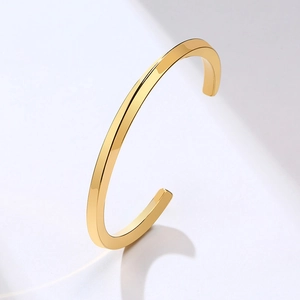 Detailed view of a polished gold twisted square wire open bangle with reflective finish