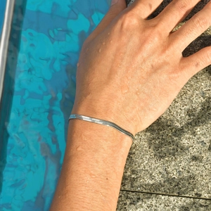 Detailed view of silver herringbone snake chain bracelet on skin with water droplets