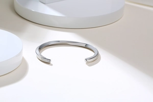 Close-up of a silver twisted stainless steel open cuff bracelet on a minimalist display