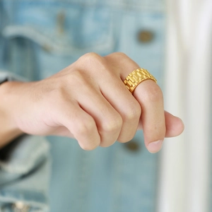 Détail d'une bague style bracelet de montre dorée au doigt avec texture métallique polie